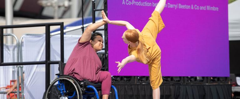 Two dancers, one in a wheelchair and one standing, perform at the 10th Anniversary London Olympics
