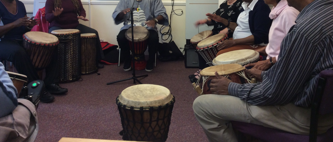 Group of people sat in a circle playing hand drums
