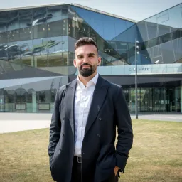 Portrait of Mete Coban, Deputy Mayor for Environment, standing outside City Hall in London.