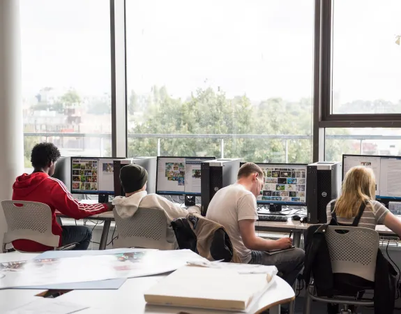 Young people sitting at desks and looking for information on computers as part of STEM programme