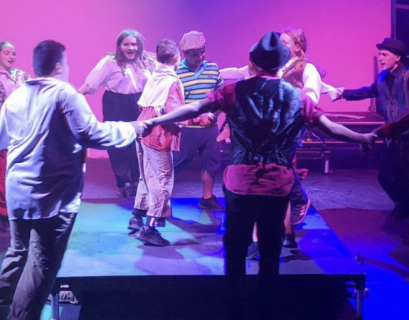 People dancing in a clircle on stage