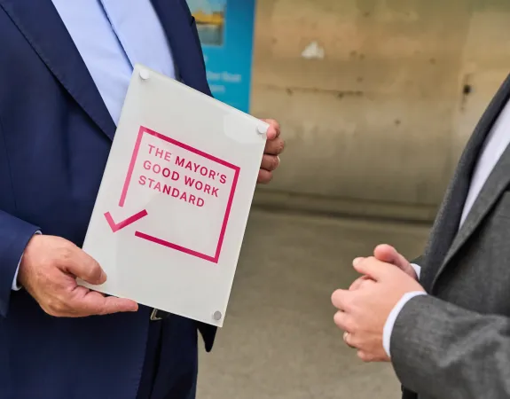 Person holding a white and pink solid plaque with good work standard on it