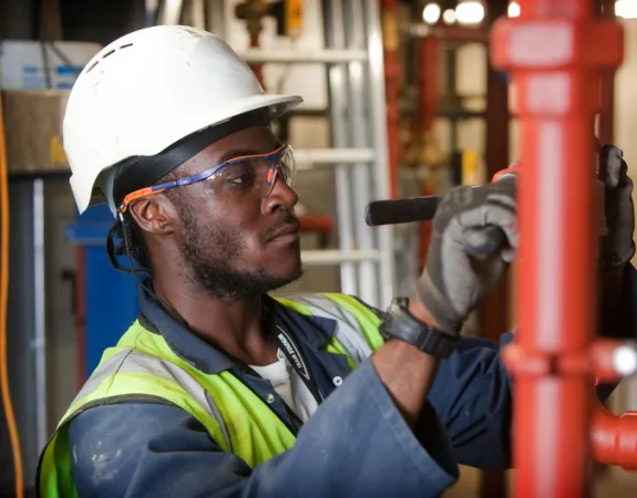 man in high viz jacket working on red pipes