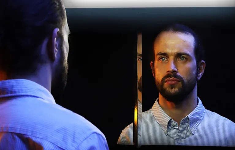 A white male looking into a mirror.