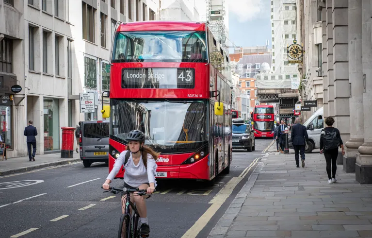 A red London bus and a cyclist on a London street