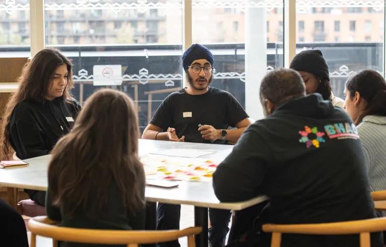 Young people sitting around a desk discussing ideas.