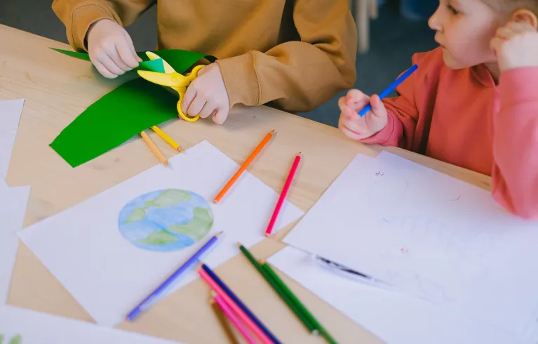 Drawing of Earth and children cutting paper with scissors