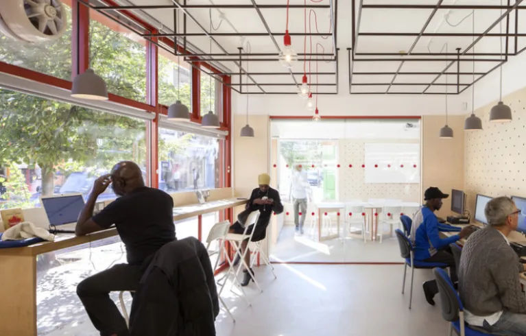 The East Street Library project. A bright room with people working while reading and at laptops and computers. Image credit: We Made That