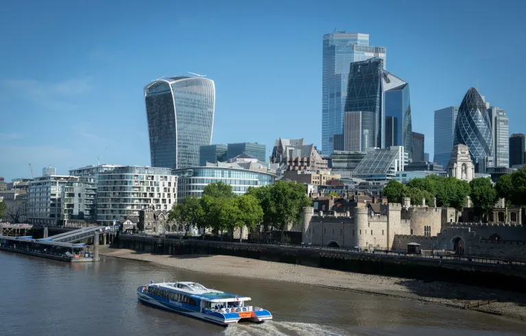 Image of London skyline with a boat in the foreground on the Thames river