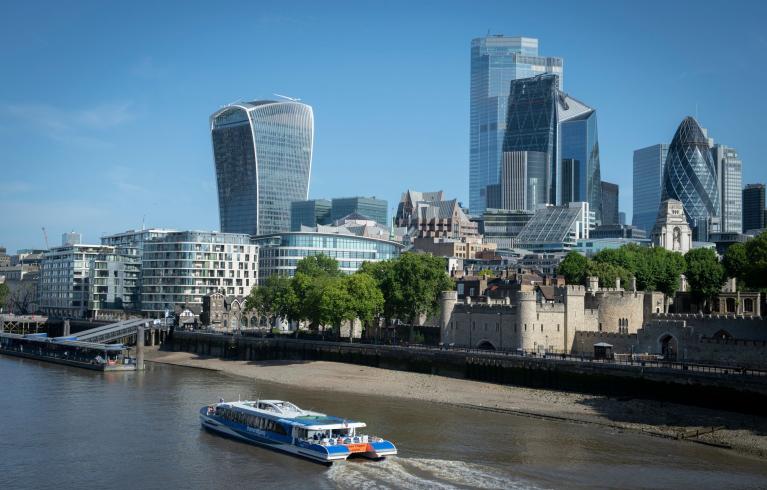 Image of London skyline with a boat in the foreground on the Thames river