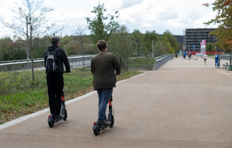 Two people riding e-scooters