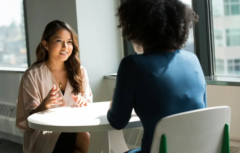 Two young women discussing at table