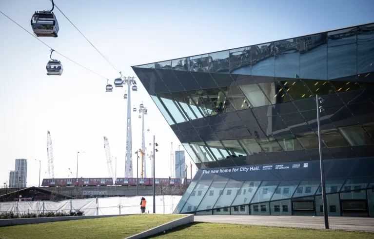 Photo of the City Hall building in East London with cable cars on wires going past the side of the building
