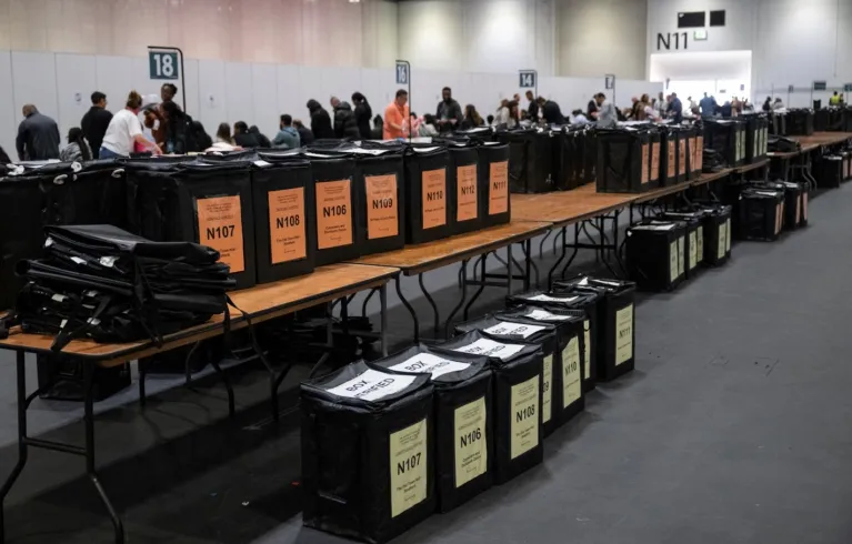 Photo of rows of ballot boxes on tables and on the floor in a polling station