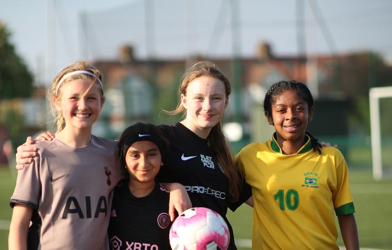 A group of four girls on a football pitch