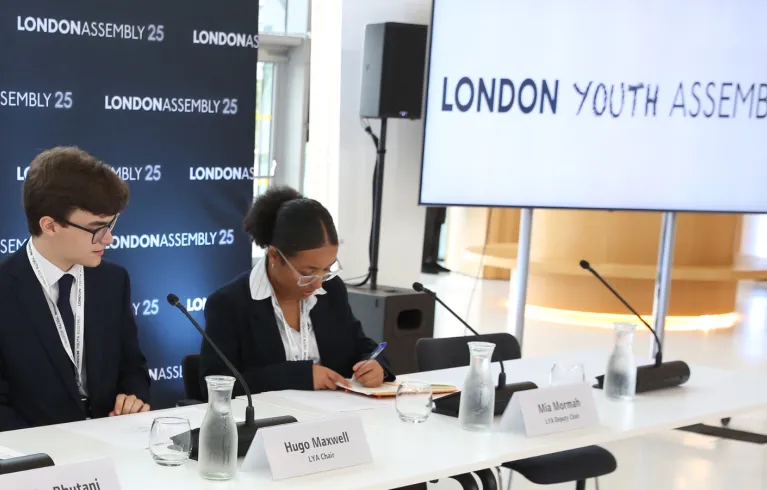 two young people with london youth assembly screen