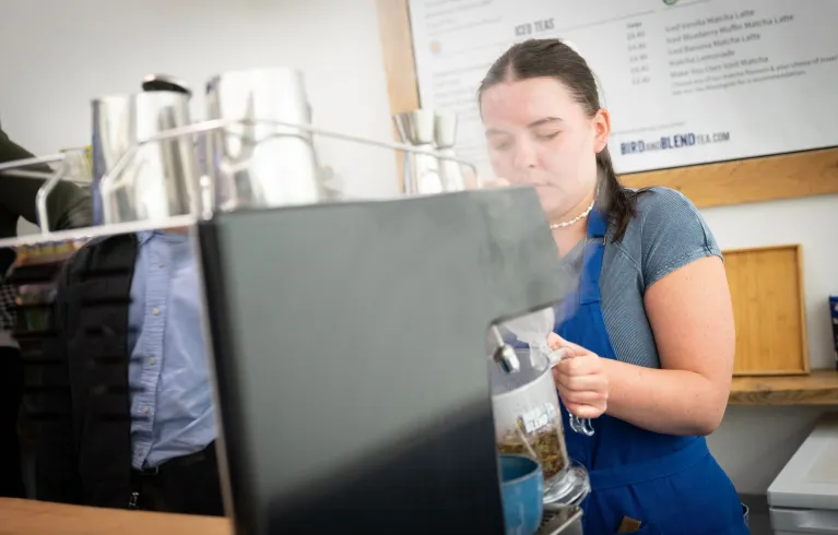 Woman steaming milk at machine