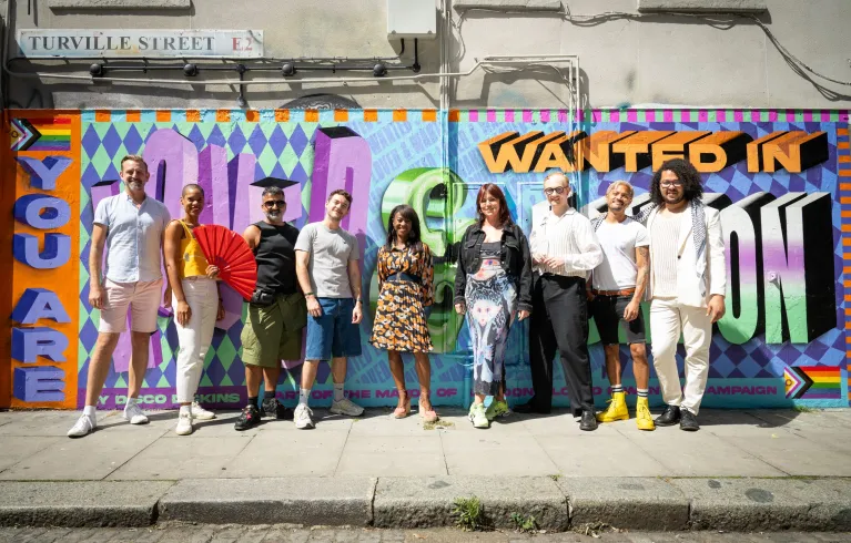 Nine Londoners stand in front of the Disco Dickins Pride Mural. Mural text says, "YOU ARE LOVED & WANTED IN LONDON". At centre stands Dr Debbie Weekes-Bernard, Deputy Mayor for Communities and Social Justice.