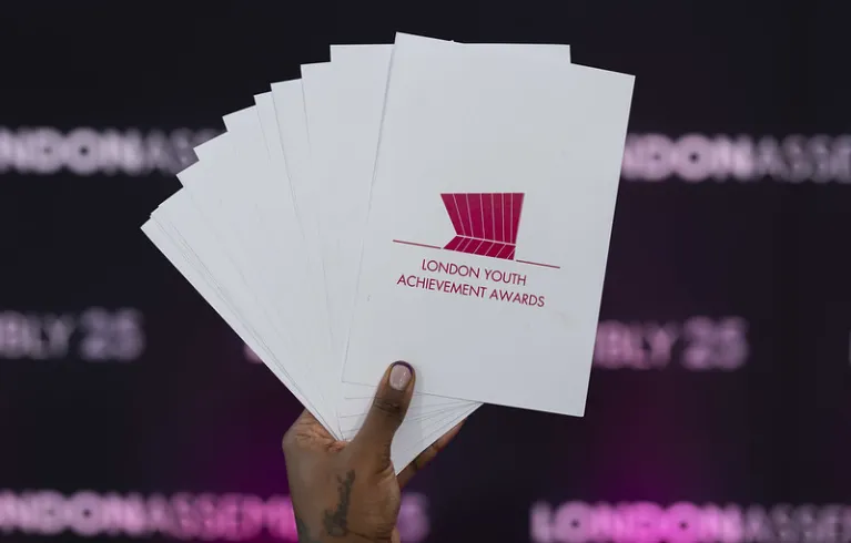 Hand holding London Youth Achievement Awards 2025 flyers