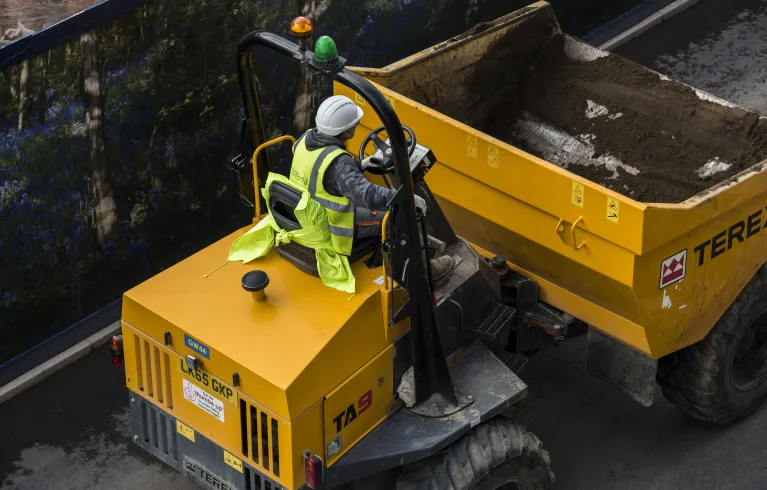 Person sat in yellow digger on construction site