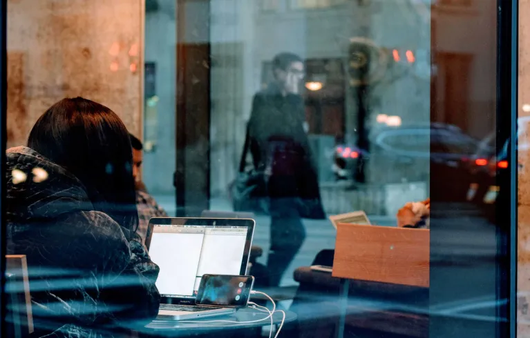 Person in cafe using laptop and phone