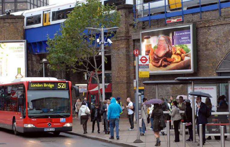 A bus arrives at Waterloo bus and train station as people wait to board.