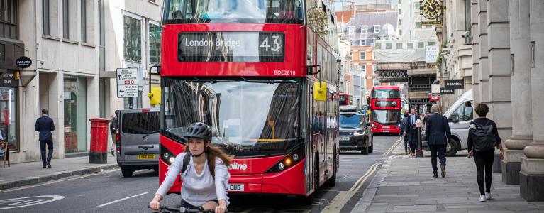 A red London bus and a cyclist on a London street