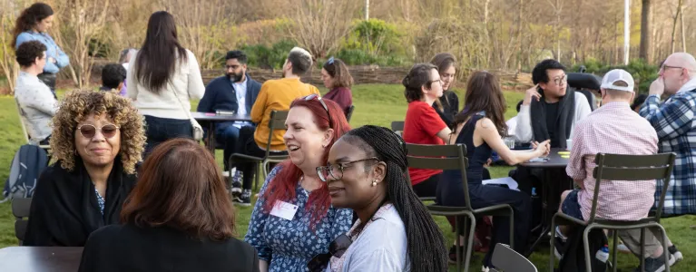 Three groups of people sit at three tables in a park having discussions. Copyright Briony Campbell 2022