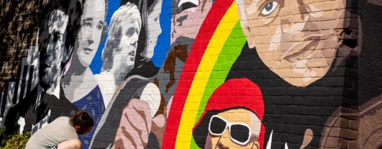 Artist working on a colourful mural showing iconic musicians from Croydon like Nadia Rose and Samuel Coleridge Taylor.