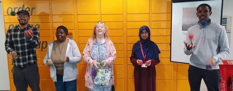 A row of people looking to camera and juggling balls