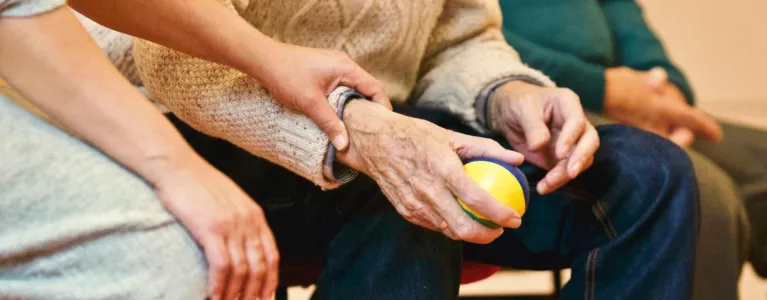 Younger person holding hands of older person holding a stress ball
