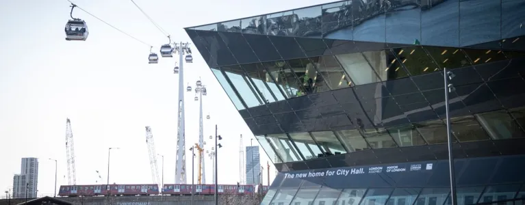 Photo of the City Hall building in East London with cable cars on wires going past the side of the building