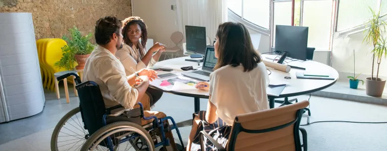 Three people sit at a table having a conversation.