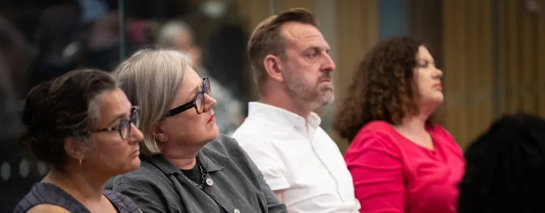 Caroline Russell sits alongside an audience, wearing a grey cardigan and black shirt.