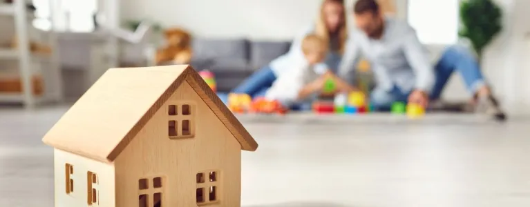 Wooden house shaped toy with family playing in the background
