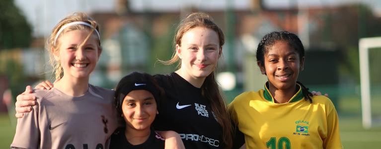 A group of four girls on a football pitch