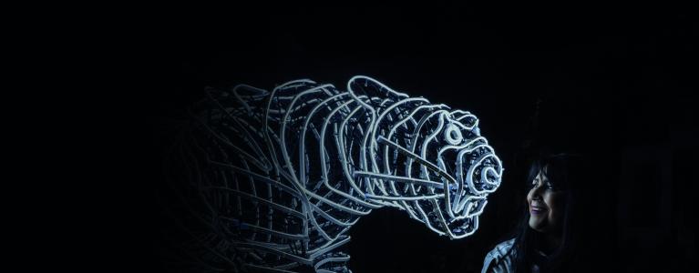 Artist Chila Burman standing next to her artwork ‘My Tiger Janu’ – a neon light sculpture of a tiger.