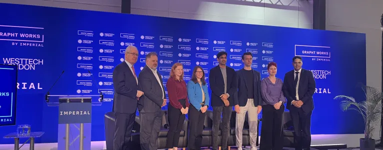 Image of a panel of speakers standing in front of a blue background.