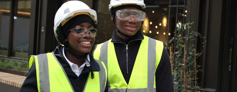 Two young people in high vis jackets and hard hats
