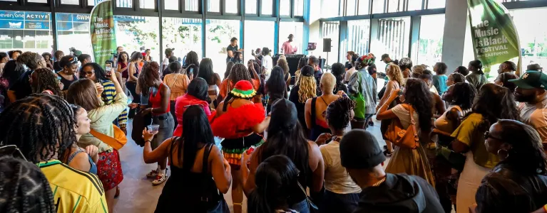 Large crowd gathered indoors at The Music Is Black Festival, watching a live performance in a bright event space