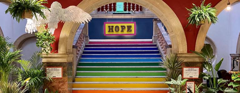 Rainbow coloured stairway with a sign at the top reading 'Hope'