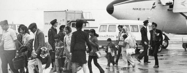 Ugandan and Asian people disembarking from a plane