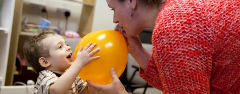Woman blowing a balloon up for a child