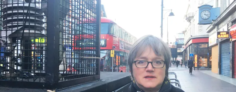 Assembly Member, Caroline Russell stands next to an air quality monitor on Brixton Road.