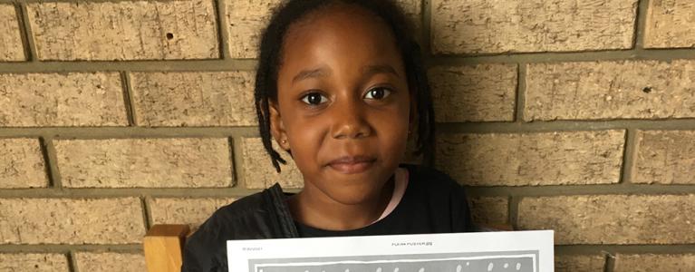 Young girl poses for photo with a Festival of Ideas poster she made