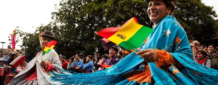 Women dancing wearing a blue dress and holding a flag