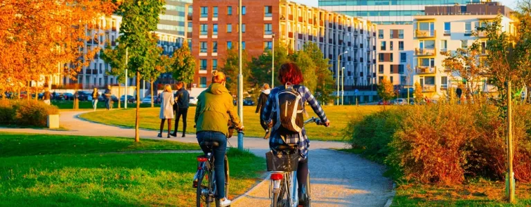 Two people cycling through a park