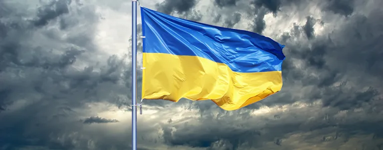 The Ukraine flag raised under a cloudy sky