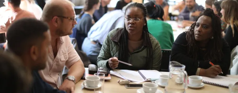 A group of people sit around a table having a discussion