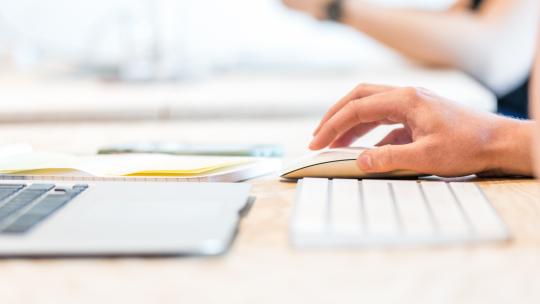 Close shot of hand of person using mouse and laptop